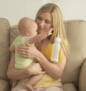 Woman holding a baby and a bottle on a couch