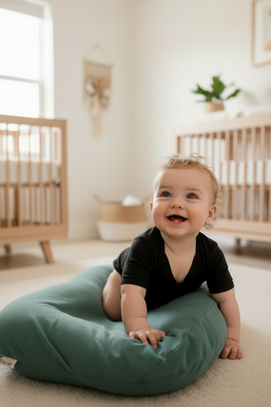 A newborn baby lying in a brown, cushioned baby lounger nest.