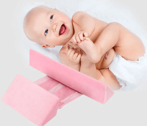A newborn baby lying on a green Anti-Roll Side Sleeper Pillow Wedge with a removable cover.