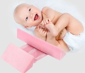 A newborn baby lying on a green Anti-Roll Side Sleeper Pillow Wedge with a removable cover.
