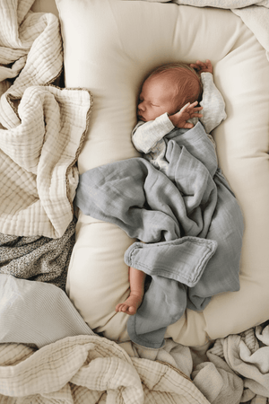 a baby sleeping in a baby lounger nest