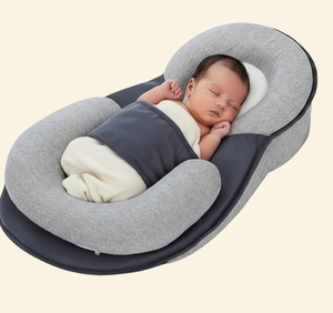 Newborn baby sleeping in a gray and navy swaddle on a matching baby lounger pillow