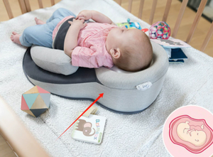 Baby lying on a cushion with toys around