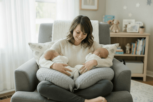 Woman breastfeeding a baby on a bed with a neutral headboard.