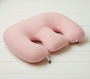 Pink travel neck pillow on a white wooden surface