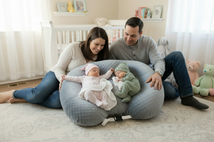 Two babies sleeping on a blue bean bag with white and blue blankets.