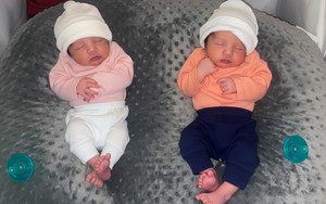 Two newborn babies lying on a textured surface with blue and white clothing.