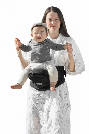 Woman holding a baby in a black baby carrier against a white background