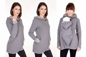 Woman wearing a gray hoodie with striped trim, holding a baby in a carrier.