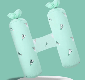 Two green cylindrical pillows with decorative bows on a light green background