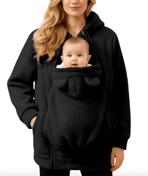 Woman wearing a black baby carrier with a baby inside on a white background