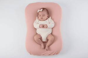 Baby lying on a pink cushion with a white background