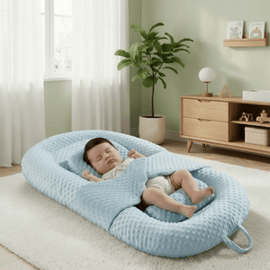 Baby lying in a blue waffle-textured baby nest in a nursery setting.