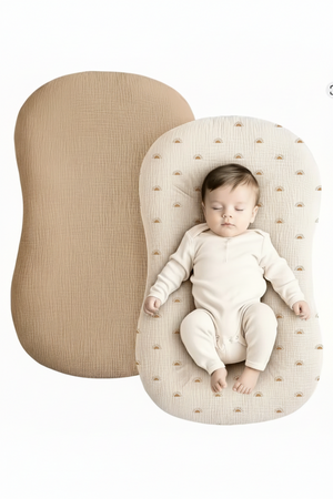 Baby lying on a textured beige cushion with a plain beige cushion next to it.