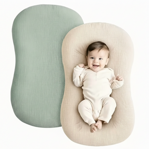Baby lying on a soft, rounded pillow with a plain background