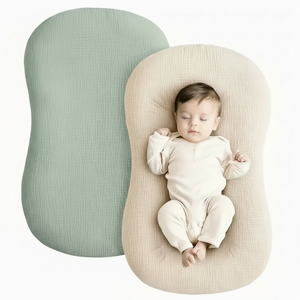 Baby lying on a soft, rounded pillow with a plain background