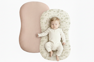 Baby lying on a floral-patterned cushion next to a pink cushion on a white background