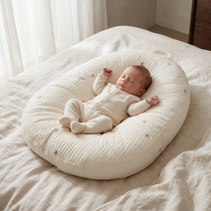 Baby sleeping on a white cushion in a softly lit room