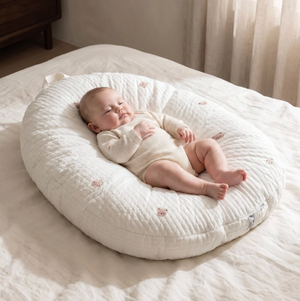 Baby lying on a white cushion in a softly lit room