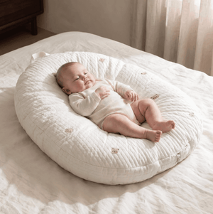 Baby lying on a white cushion in a softly lit room