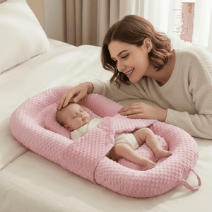 Woman with a baby in a pink baby nest on a couch