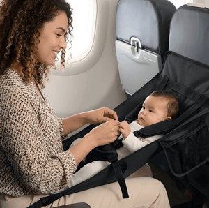 Woman securing a baby in an airplane seat with a car seat