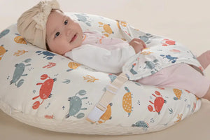 Baby lying on a wedge-shaped pillow with a 15-degree angle, wearing a patterned outfit and headband.