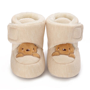 Beige baby booties with bear face design on a white background