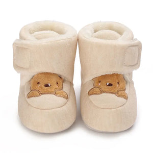 Beige baby booties with bear face design on a white background