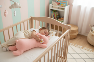 Child sleeping in a crib with a pink teddy bear in a nursery.