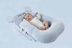 Baby lying in a blue baby nest with a light blue background
