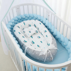 Baby nest with tree pattern in a crib with blue bedding