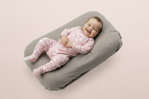 Baby lying on a gray cushion with a light green background