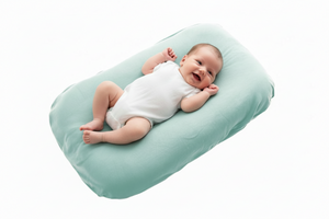 Baby lying on a light green baby lounger nest baby pillow against a white background