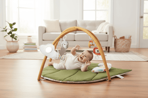 Baby playing with a green activity gym on a white floor