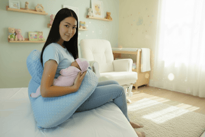Woman holding a baby with a blue support pillow in a nursery setting
