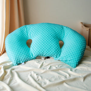 Turquoise U-shaped pillow on a bed with beige bedding