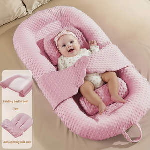 Baby in a pink crib with a smiling expression on a beige bed.