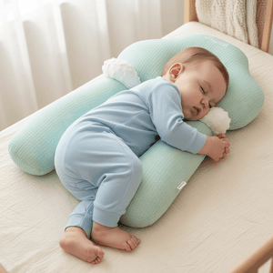 Baby sleeping on a green pillow with a soft toy