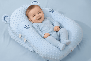 Baby in a blue crib with bear ears on a beige background