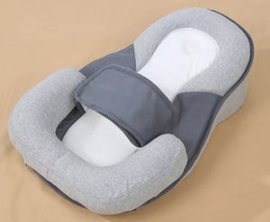 Gray and white baby lounger pillow on a beige background