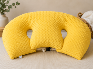 Yellow U-shaped pillow on a beige surface with a plant and basket in the background