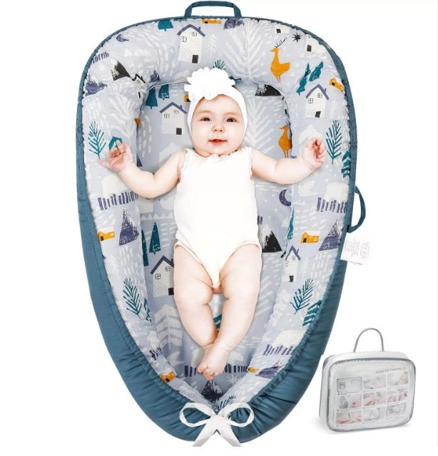 Baby lying in a patterned baby nest with a matching carrying case on a white background