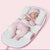 A baby lying on a green and white anti-reflux and anti-roll baby lounger bed.