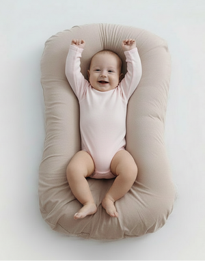 Baby lying on a beige baby lounger against a white background