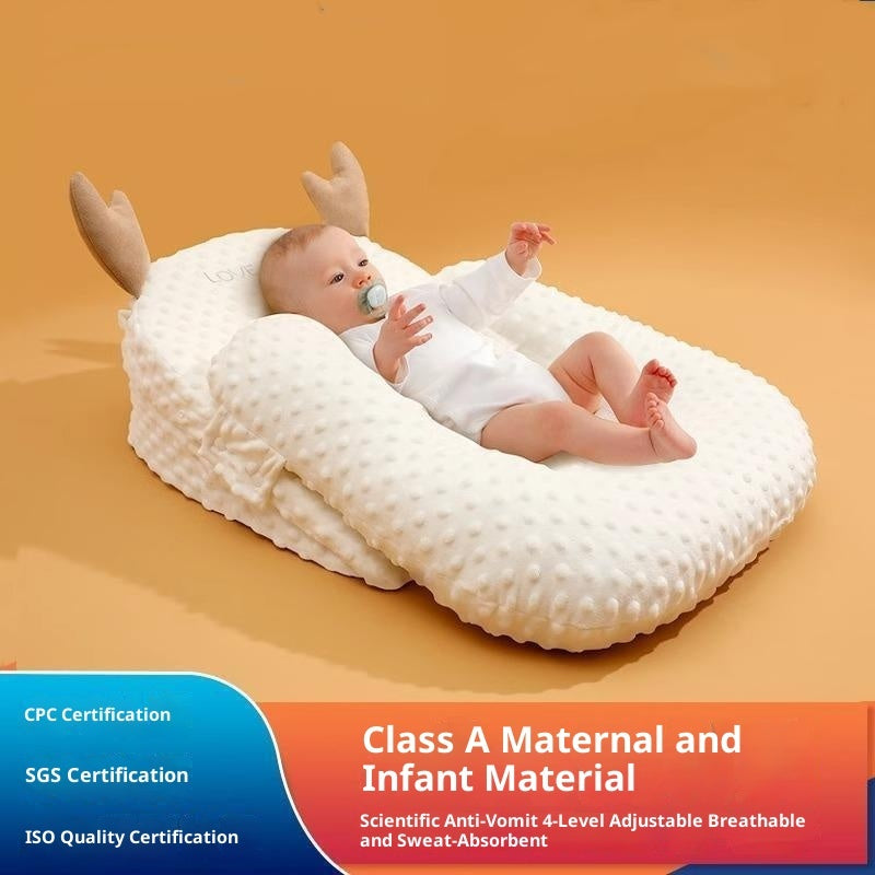 Baby lying on a white pillow with antler-like decorations against an orange background