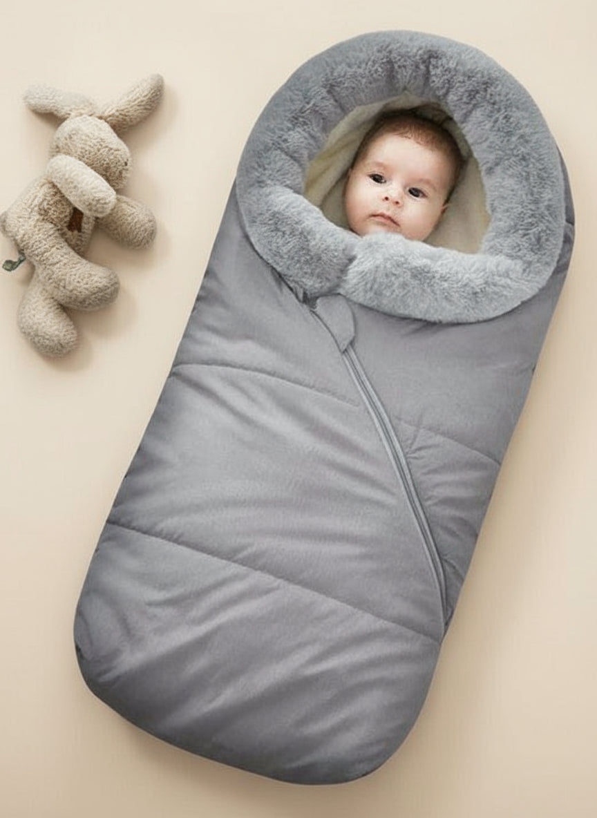 A baby sleeping bag with a gray outer layer, coral fleece middle layer, and a faux fur collar, designed to be windproof and warm.