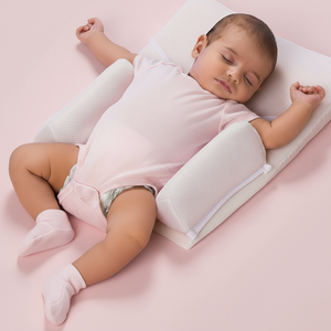 Baby sleeping on a pink blanket with a white wedge pillow