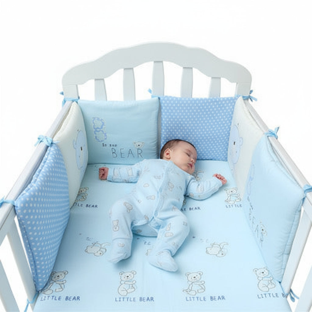 Baby crib with blue crib bumper and pillow set on a white background