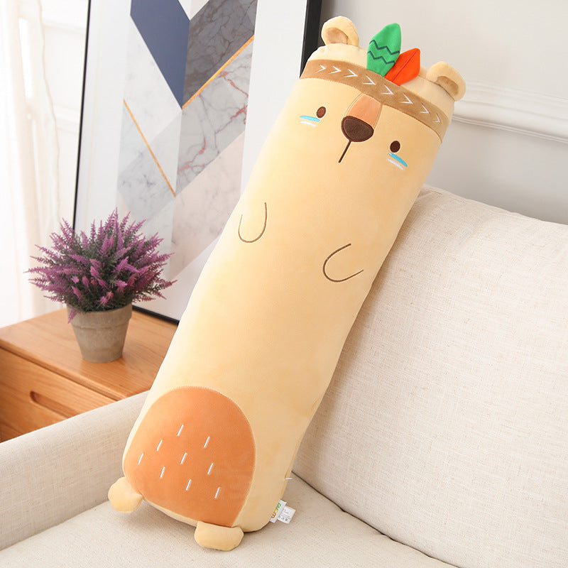 Long cylindrical bear-shaped pillow on a couch with decorative elements in the background